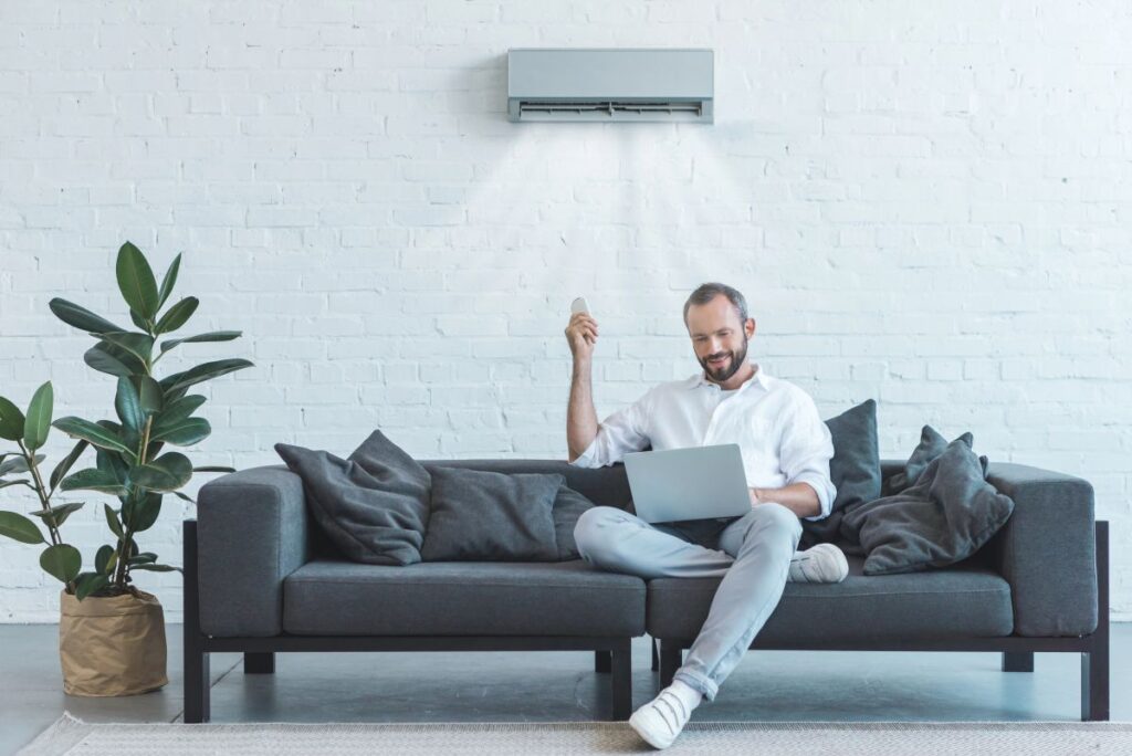 A man resting behind an air conditioning working properly showing how much should an air conditioning system last.