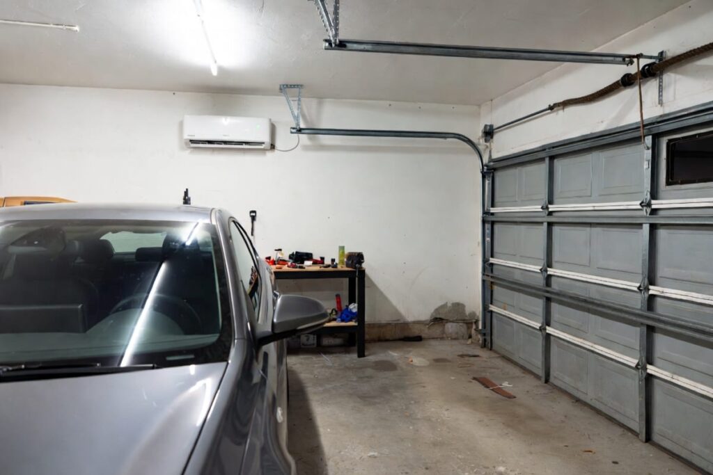 A garage with a car, some tools and a mini split installed inside it, showing that you can install a mini split in a garage.