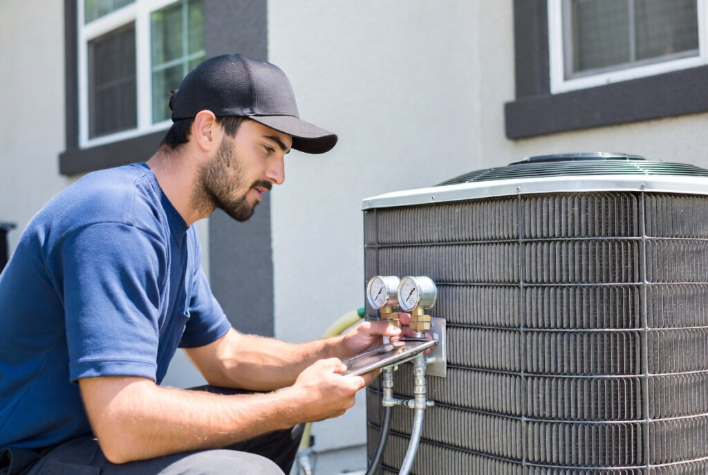 Technician using pressure gauges for a diagnostic check during professional pre summer hvac maintenance service.