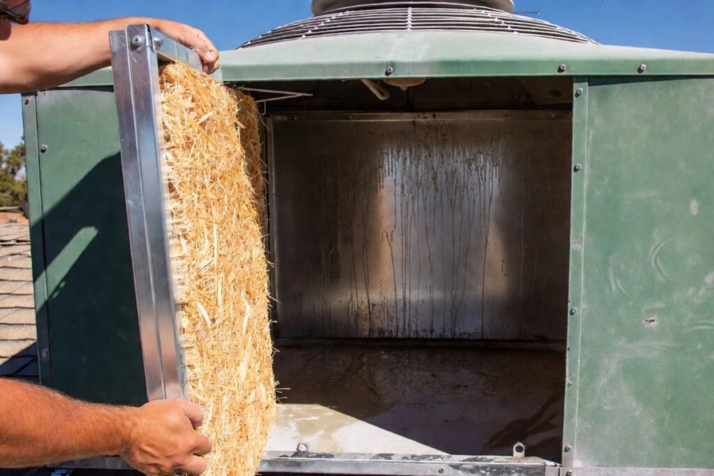Technician installing a new aspen wood fiber pad to show when to change swamp cooler pads for better cooling.