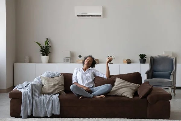 A woman using an AC that doesn't cool, showing the importance of fixing an AC that is running but not cooling the house.