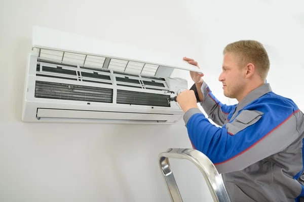 Technician performing maintenance on a split system to identify what causes an AC capacitor to fail for an AC homeowner.