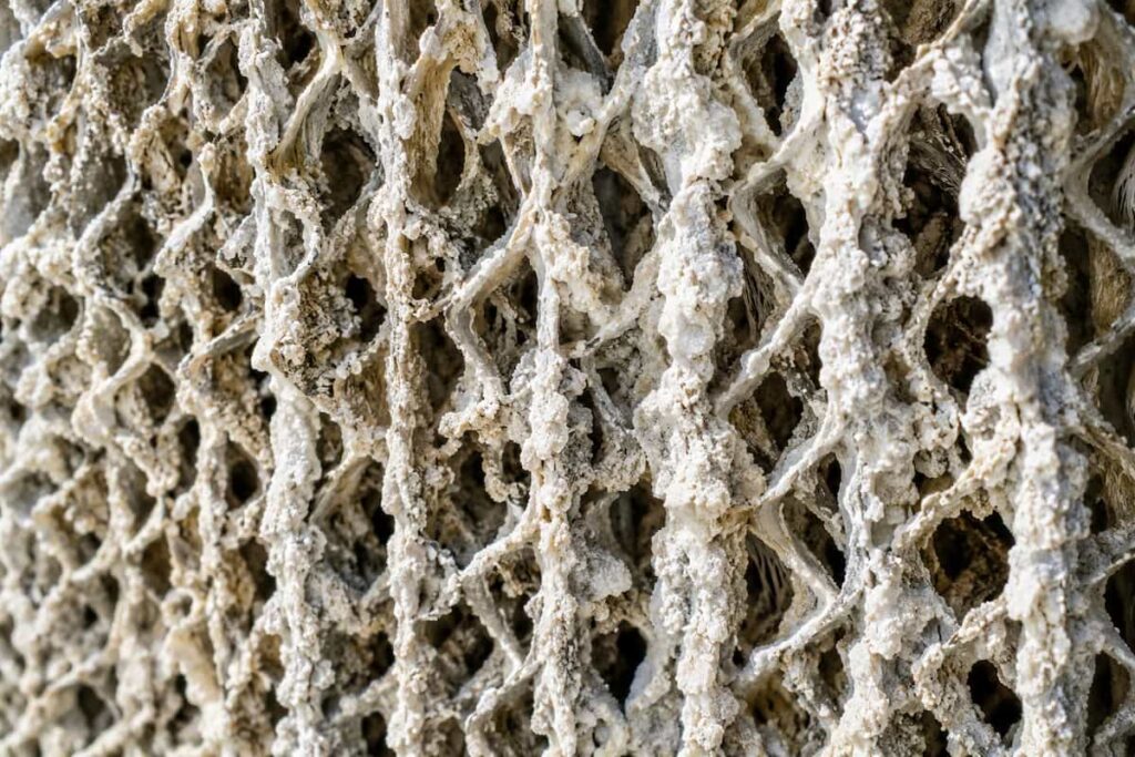 Severe scale shows how hard water affects swamp cooler pads by coating the rigid media fibers in heavy calcium crust.